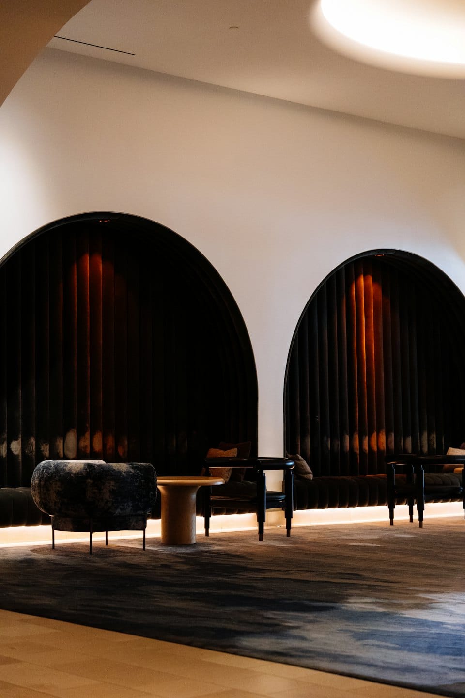 Modern lounge with velvet seating alcoves and wood furniture.