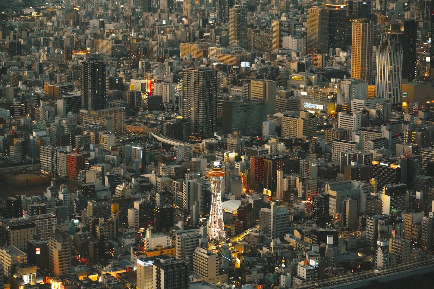 A brightly lit observation tower rises above a dense city.