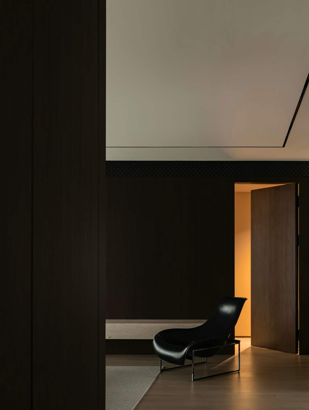 Black leather chair near an open door with an orange glow.