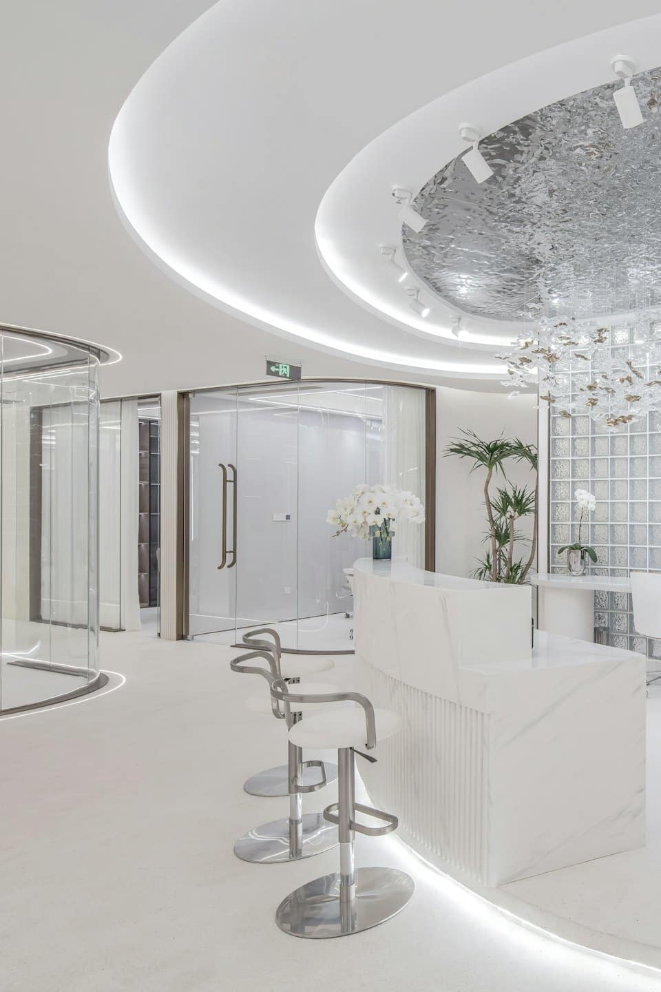 Modern office reception area with marble desk and plants.